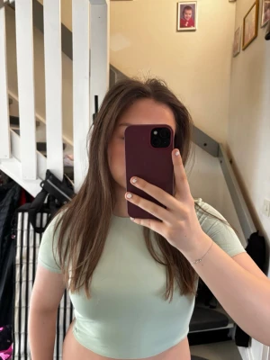 Ljusgrön croppad t-shirt - Snygg ljusgrön croppad t-shirt med korta ärmar och rund halsringning. Perfekt för dig som gillar en enkel och fräsch stil. T-shirten är i mjukt material och passar till många olika outfits.💖