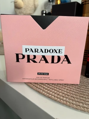 Prada Paradoxe Intense EdP - Prada Paradoxe Intense Eau de Parfum är en lyxig parfym med en unik trekantig flaska i rosa glas och svart kork. Förpackningen är ljusrosa med svart och vit text. Parfymen är påfyllningsbar och passar dig som gillar exklusiva dofter.