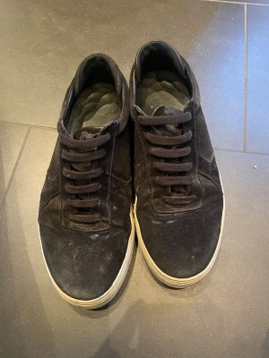 Svarta sneakers från Axel Arigato - Säljer ett par svarta sneakers från Axel Arigato i storlek 41. Skorna har ovandel i mocka och detaljer i skinn, med klassisk snörning och vit platt sula. 