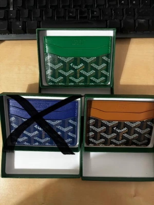 Gyard korthållare i grönt och brunt - Snygga korthållare från Goyard i klassiskt mönster. En är grön med vit logga och detaljer, den andra är brun med samma ikoniska mönster. Tillverkade i exklusivt läder med flera fack för kort. Perfekt accessoar för dig som gillar stilrena detaljer.