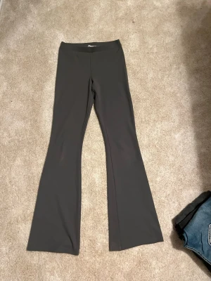 Mörkgrå utsvängda leggings 157 - Säljer ett par mörkgrå leggings från 157 i storlek XS. De har utsvängda ben och är sydda i ett stretchigt, mjukt material som sitter skönt på kroppen. Perfekta för dig som gillar en enkel men trendig look med lite retrovibbar.