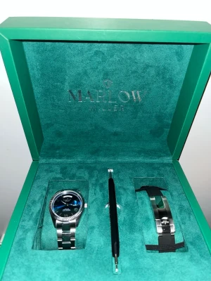 Marlow Miller silverfärgad klocka - Snygg klocka från Marlow Miller med silverfärgad länk och blå urtavla. Kommer i exklusiv grön box med extra armband och verktyg för byte. Klockan har en klassisk rund form och stilren design som passar till många olika looks.