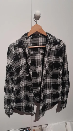 Rutig skjorta - En svart och vit rutig skjorta med knappar. Tunnt material.