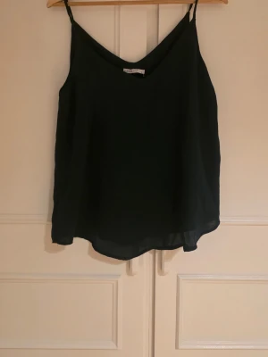 Mörkgrön  linnetopp med tunna axelband - Snygg svart linnetopp med tunna axelband och v-ringad hals. Aldrig använd