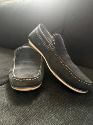 Marinblå mocka loafers med vit sula - Snygga marinblå loafers i mocka med kontrasterande vita sömmar och vit sula. Jag har inte haft på mig dom mycket. Passar perfekt till storlek 44. Nypris 750kr