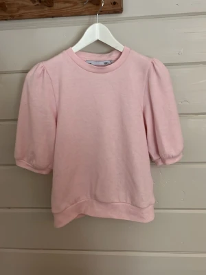 Ljusrosa topp med puffärm - Supersöt ljusrosa topp med puffiga kortärmar från lager 157. I storlek S