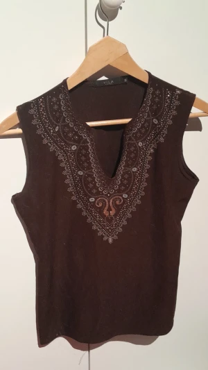 Brun topp - En brun topp med glitterdetaljer.