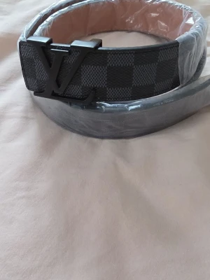 rutigt bälte svart/grå - Snyggt bälte i rutigt mönster och svart och grått. Perfekt accessoar för att lyfta din outfit.