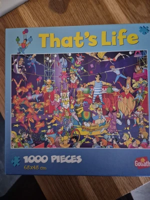 That's Life pussel 1000 bitar - Roligt och färgglatt pussel från Goliath med motiv av en cirkus fylld av tecknade figurer och galna upptåg. Pusslet har 1000 bitar och mäter 68x48 cm när det är färdigt. Perfekt för dig som gillar utmanande och detaljrika pussel.