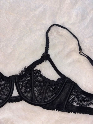 Svart spets-bh med bygel - Svart oanvänd bh med bygel och transparent spetsdetaljer. Bh:n har tunna, justerbara axelband och mönstrad spets över kuporna. 