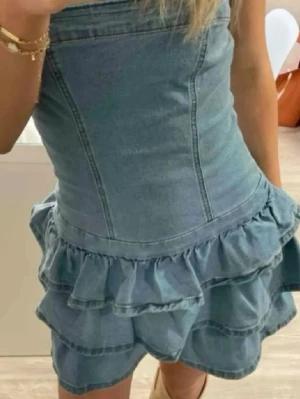 Volangklänning i denim - Jättefin volangklänning i denim med volanger och snatchad midja som formar kroppen så snyggt!! Klänningen är stretchig och har klisterband så den ej åker av!!! Storlek xs och nyskick😍😍