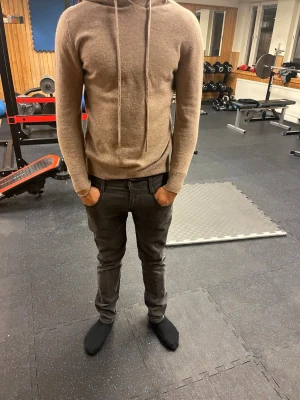 Kashmir hoodie - Säljer en beige hoodie i mjuk och skön ullmix. Hoodien har dragsko i huvan, ribbade muddar vid ärmslut och nederkant samt en avslappnad passform. Perfekt för dig som gillar stilrena och bekväma plagg.