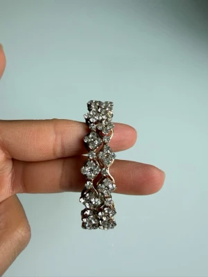 Glittrigt armband med strasspärlor - Snyggt armband i silverfärg med två rader glittrande strasspärlor. Armbandet har ett flätat mönster som ger en lyxig och trendig känsla. Perfekt accessoar för dig som vill sticka ut och addera extra bling till din outfit.