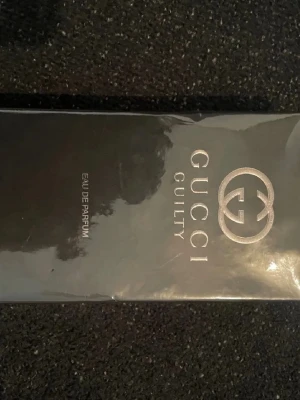 Gucci Guilty Eau de Parfum - Gucci Guilty Eau de Parfum i en elegant svart kartong med silverfärgad logotyp och text. Parfymen har en lyxig känsla och är perfekt för dig som vill ha något exklusivt. Materialet på förpackningen är kartong med metallic-detaljer.