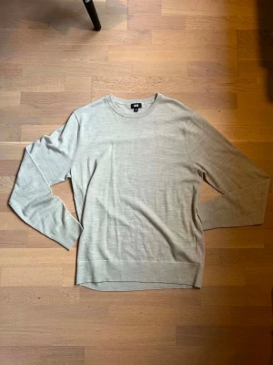 Beige stickad tröja från Uniqlo - Snygg beige stickad tröja från Uniqlo med rund halsringning och långa ärmar. Tröjan har en enkel och stilren design, perfekt att matcha med jeans eller kjol. Tillverkad i ett mjukt och tunt stickat material som känns skönt mot huden.