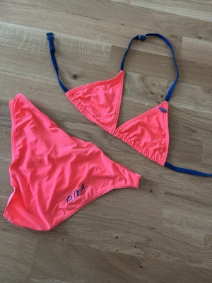 Rosa bikini från O'Neill - Snygg rosa bikini från O'Neill med trekantsöverdel och mörkblå knytband. Bikinitrosan har O'Neill-logga på sidan. 