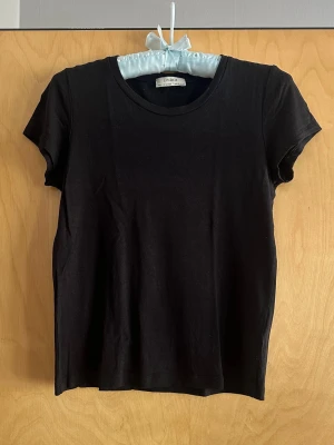 Svart basic t-shirt från Lindex - En enkel svart t-shirt från Lindex med rund halsringning och korta ärmar. 