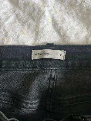 Svarta raka jeans från Perfect Jeans - Säljer ett par svarta jeans från Perfect Jeans i storlek 36. Jeansen har rak passform, klassisk femficksdesign och normal midja. Materialet är mjukt och stretchigt för en bekväm känsla. Perfekta till en enkel topp eller hoodie.