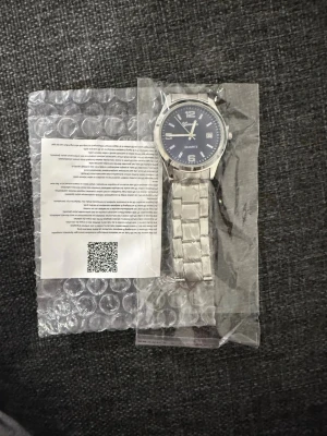 Silverfärgad klocka från Geneva - Stilren klocka från Geneva med silverfärgad metallarmband och mörkblå urtavla. Klockan har tydliga siffror, datumvisning och klassisk design. Perfekt accessoar för dig som gillar en clean look.