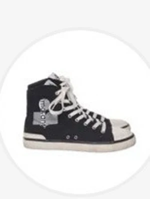 Marant skor - Snygga svarta high top sneakers med vita snören och sula. Skon har en vit tåhätta och coola tryck på sidan. Klassisk retrostil med kontrasterande detaljer och metallöljetter för snörningen. Perfekt för dig som gillar streetwear och vill sticka ut.
