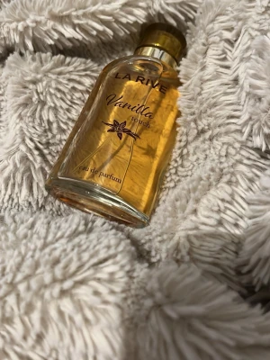 La Rive Vanilla Touch parfym - La Rive Vanilla Touch är en eau de parfum med söt och varm vaniljdoft. Flaskan är genomskinlig med guldigt lock och detaljer, och innehållet har en ljus bärnstensfärg. Perfekt för dig som gillar mjuka och krämiga doftnoter.