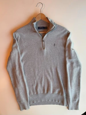 Ljusgrå stickad tröja Polo Ralph Lauren - Snygg ljusgrå stickad tröja från Polo Ralph Lauren med halvzip. Skick hade varit 10/10 om det inte hade varit ett litet rivmärke på höger arm. De syns dock inte mycket och går inte igenom tyget. Det är bara att höra av er vid frågor. Pris kan diskuteras.