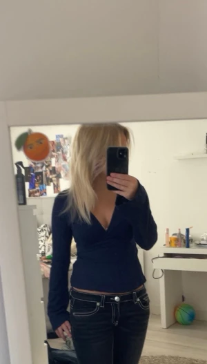 Mörkblå omlottblus med långa ärmar från Gina storlek xs - Snygg mörkblå omlottblus från Gina Tricot med långa ärmar och knytband i midjan. Blusen har en djup v-ringning och är tillverkad i ett mjukt, stretchigt tyg som sitter bekvämt. .