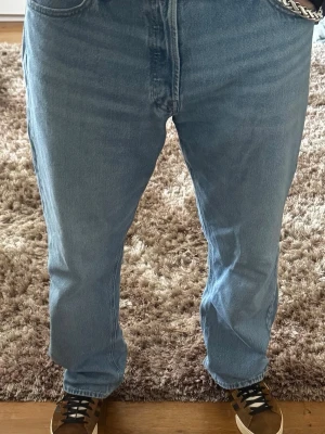 Ljusblå raka jeans i klassisk modell - Säljer ett par ljusblå jeans med rak passform och hög midja. Jeansen har fem fickor och stängs med dragkedja och knapp. Perfekta till sneakers och t-shirt för en avslappnad look. Materialet är mjuk denim i bomull.