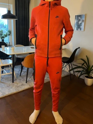 Röda mjukisbyxor från Nike - Säljer ett par röda mjukisbyxor från Nike med smal passform och svarta detaljer längs sidorna. Byxorna har dragsko i midjan och är tillverkade i mjukt material, perfekt för chill eller träning.