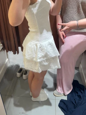 Smock frill dress - Supersöt vit kort klänning med smockad överdel och dubbla volanger i kjolen. Klänningen har fina spetsdetaljer och broderade blommor på kjolen. Perfekt för sommarens alla tillfällen! Från Gina tricot och säljs inte längre🥰 älskar denna klänning men nu är de dags att släppa taget💞 