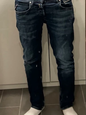 Mörkblå raka jeans från Replay - Säljer ett par mörkblå jeans från Levi's med klassisk femficksmodell och raka ben. Jeansen har subtila slitningar och kontrastsömmar, samt Levi's ikoniska bakficka med röd etikett. Perfekta för en avslappnad och stilren look.