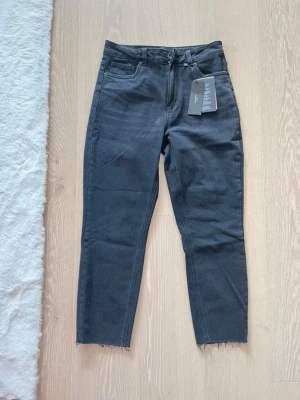 Svarta straight jeans Vero Moda - Snygga svarta jeans från Vero Moda i modellen VMBrenda HR Straight. Jeansen har hög midja, raka ben och råa benslut. Tillverkade i svart denim med klassisk femficksdesign och dragkedjegylf.