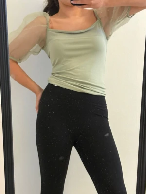 Ljusgrön topp med puffärmar - Snygg ljusgrön topp med transparenta puffärmar och bred, rund halsringning. Toppens kropp är i mjukt material och ärmarna är i tunn mesh som ger en cool look. Perfekt för dig som vill sticka ut med trendiga detaljer.