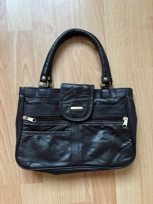 Mörkbrun Läder Väska Med Guld Detaljer - En jättefin men använd mindre väska. Perfekt för en night out och har måttligt med utrymme. INTE från SHEIN.  19x29. Tar gärna emot bud, skriv om ni har frågor 💕