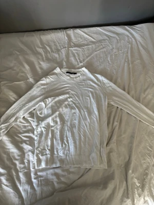 Vit tröja från 157 med rund hals - Vit långärmad tröja från 157 med klassisk rund halsringning och ribbade muddar. Enkel och stilren design som passar perfekt till jeans eller chinos. Materialet är mjukt och bekvämt, perfekt för lager-på-lager under kyliga dagar.