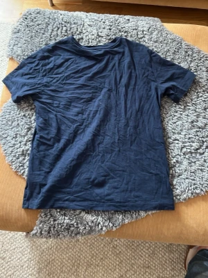 Mörkblå t-shirt från gant - Säljer en mörkblå t-shirt från gant med klassisk passform och korta ärmar. T-shirten har en liten broderad logga på bröstet och är tillverkad i mjuk bomull. Perfekt för dig som gillar stilrena basics.