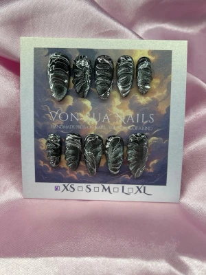 NightDust (XS);Medium Almond - Unika handgjorda press-on naglar i svart med detaljerat handgjord nailart i silvermönster. Naglarna har en medium lång mandelformad design och cool cateye metallic look som verkligen sticker ut. Perfekt för dig som vill ha något edgy och konstnärligt på naglarna.XS: 14 mm, 11 mm, 11,5 mm, 10 mm, 8 mm 