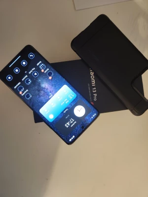 Xiaomi 13 Pro Android mobiltelefon - Snygg Xiaomi 13 Pro med stor, böjd skärm och elegant svart finish. Telefonen har en modern design med tunna kanter och levereras med ett svart skyddsfodral. Perfekt för dig som vill ha en kraftfull Android-mobil med stilren look.