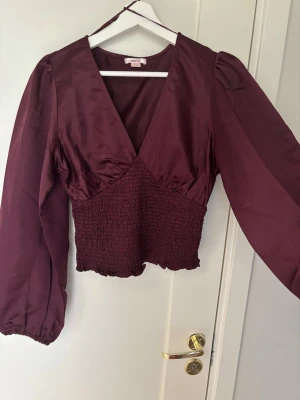 Vinröd blus med smock och v-ringning - Vinröd blus från Gina young, använt 1 gång. 