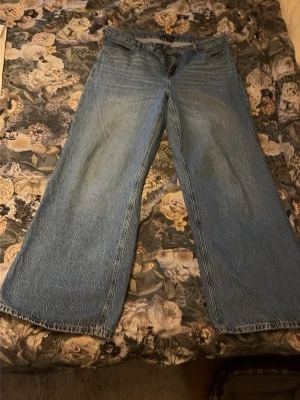 Blåa wide leg jeans - Säljer ett par blåa wide leg jeans med hög midja och klassisk femficksdesign. Jeansen har raka, vida ben och är tillverkade i denim. Perfekta för en avslappnad och trendig look.