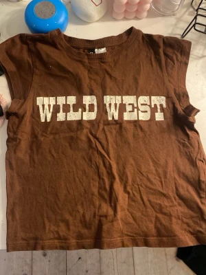 Wild west topp - Cool brun topp med text ”wild west”. Storlek xs, 160 från hm divided. 