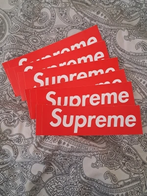 Supreme röda klistermärken - Säljer flera klassiska Supreme box logo klistermärken i starkt röd färg med vit text. Perfekta att sätta på laptop, skateboard eller andra accessoarer för att ge dem en hypebeast-touch. Materialet är slitstarkt och sticker ut med den ikoniska designen.