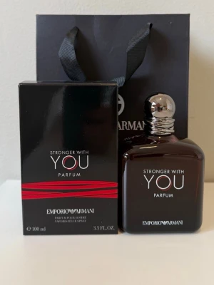 Stronger With You Parfum 100ml Armani - Stronger With You Parfum från Emporio Armani är en elegant parfym i en mörkbrun glasflaska med silverfärgad rund kork. Flaskan och kartongen har stilrena röda detaljer och modern design. Perfekt för dig som vill ha en exklusiv och kraftfull doft.