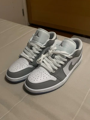 Nike Air Jordan 1 Low grå/vit - Nya Nike Air Jordan 1 Low sneakers i vitt och ljusgrått läder. Låg modell som passar perfekt till streetwear och casual outfits. Använda bara 1 gång och passade inte foten.