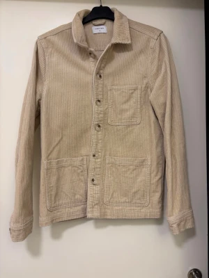 Jacka - Jättefin jacka, perfekt till sommaren! Ficka på bröstet och 2 fickor nertill. Knappar hela vägen, även vid ärmarna. Jättefint skick!