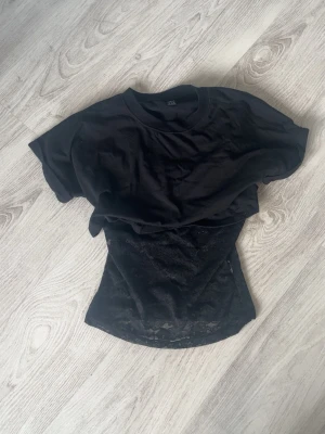 Svart croppad t-shirt med spetslinne - Säljer en svart T-shirt med ett spetslinne som tillsammans blir jättesnyggt(finns likadan i vit i min profil) 💗Kolla in min profil för fler fina och trendiga plagg!