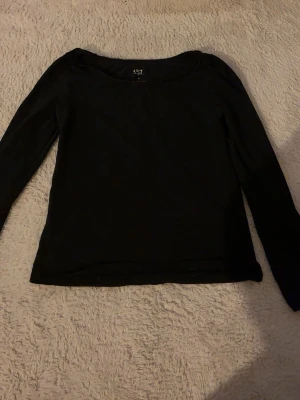 Svart långärmad topp från 157 - En enkel och stilren svart långärmad topp från 157. Tillverkad i mjuk bomull med lite elastan för extra stretch och bekväm passform. Perfekt basplagg med rund halsringning och normal passform.