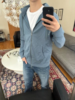 Blå zip hoodie med tryck - Säljer en blå zip hoodie. Med coolt tryck på ryggen.