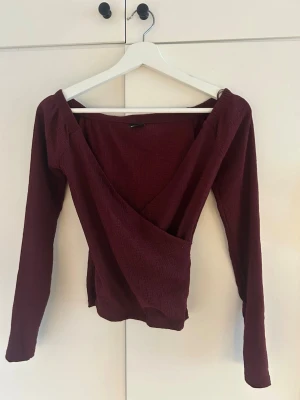 Vinröd omlottopp med v-ringning - Vinröd omlottopp med djup v-ringning och långa ärmar. 