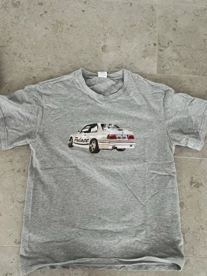 Grå T-shirt  - Säljer en snygg grå T-shirt i storlek M men kan absolut passa S också. Trycket är inte slitet och det finns inga skador eller fläckar på tröjan. Den är inte från märket palace. Få ett paketpris för båda T-shirtar för 300kr(kolla min profil)